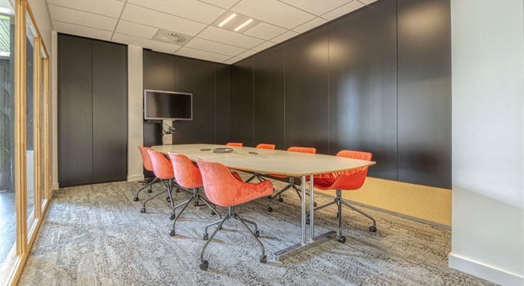 une salle de réunion avec une grande table et des sièges roses sur roulettes