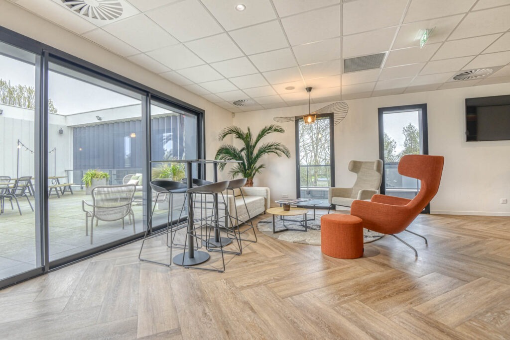 un grand espace caféteria avec du mobilier lounge et design et une terrasse exterieure avec du mobilier